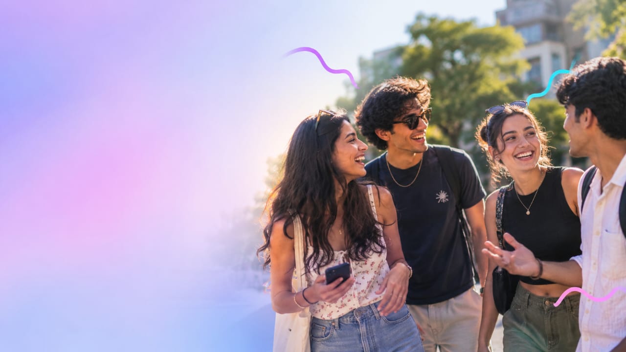 Four friends laughing together while walking outside on a sunny day
